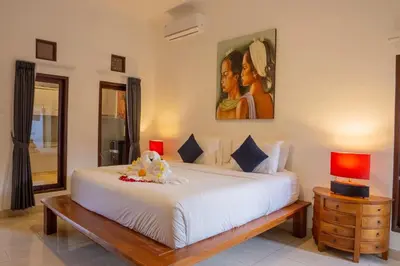 a bedroom with a white bed and a painting on the wall at VIlla Dafne in Seminyak