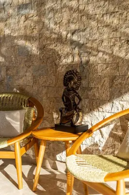a statue sitting on a table next to two chairs at Nococu Luxury Villa in Seminyak