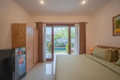 a bedroom with a bed and a sliding glass door at Titeng Guest House - Comfortable studio in amazing location near Potato Head and the beach in Seminyak