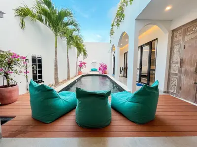 a swimming pool with green pillows on a wooden deck at Villa Paros 3BR Greek Island Villa in Seminyak in Seminyak