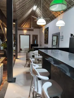 a bar in a room with white chairs and tables at JOJOBY sunset villa in Seminyak