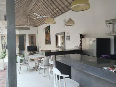 a kitchen with a bar with chairs and a table at JOJOBY sunset villa in Seminyak
