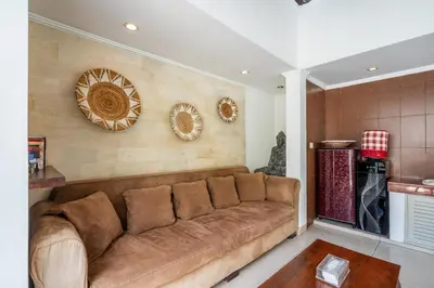 a living room with a brown couch and plates on the wall at Zen Villas by iBali Management in Kerobokan