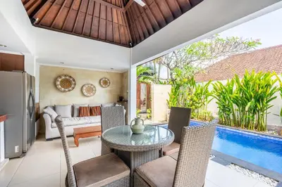 a living room with a table and chairs and a pool at Zen Villas by iBali Management in Kerobokan