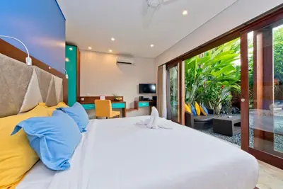 a bedroom with a large bed with blue and yellow pillows at Villa True Colors in Legian