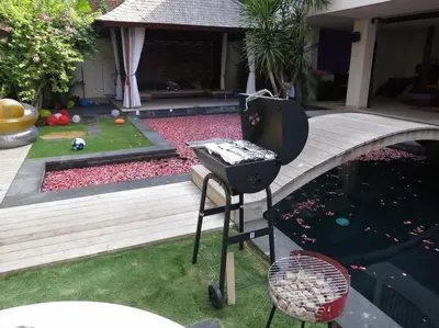 a barbecue grill next to a pool of water at Villa True Colors in Legian
