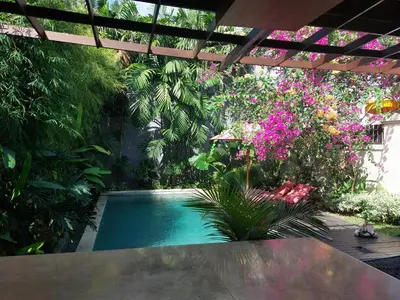 a swimming pool in a garden with pink flowers at Seminyak Beach Villa Ashira SUPERB Location in Seminyak