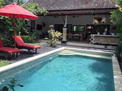 a pool in a backyard with a red umbrella and chairs at Seminyak Beach Villa Ashira SUPERB Location in Seminyak