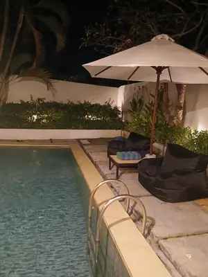 an umbrella and chairs next to a swimming pool at night at Villa Pool Private and Romantic In Kuta Bali in Kuta