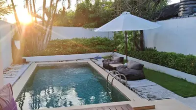 a swimming pool with two chairs and an umbrella at Villa Pool Private and Romantic In Kuta Bali in Kuta