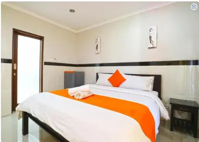 a bedroom with a large bed with an orange and white blanket at Rena Segara House Kuta in Kuta