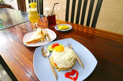 a table with two plates of food on a table at Rena Segara House Kuta in Kuta