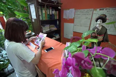 a woman is sitting at a table reading a book at Rena Segara House Kuta in Kuta