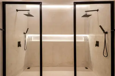 a bathroom with a shower with glass doors at Casa De La Vida in Legian