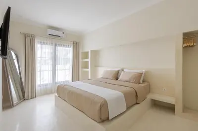 a white bedroom with a large bed and a window at Casa De La Vida in Legian
