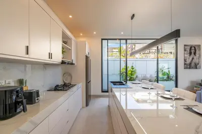 a kitchen with white cabinets and a counter top at Serai Villa by Betterplace in Seminyak