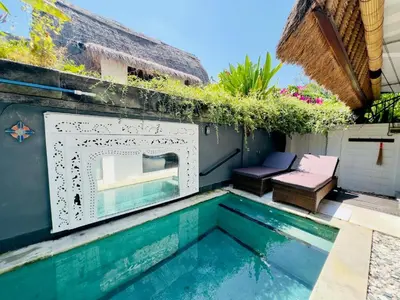 a swimming pool next to a house at Tiga Kelapa Villa by Smart Digital in Legian