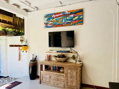 a living room with a tv on a white wall at Tiga Kelapa Villa by Smart Digital in Legian