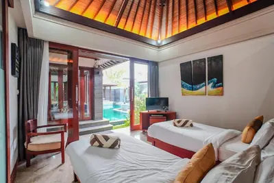 a bedroom with two beds and a tv and a couch at Villa Di Bucu, Canggu in Canggu