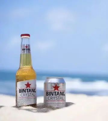 a bottle of beer and a can on the beach at 9 Residences Seminyak in Seminyak