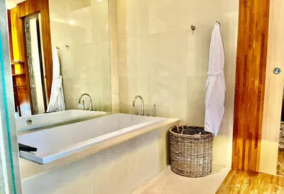 a bathroom with a tub and a mirror and a basket at 450 квадратных метров, Вид на Рисовое Поле и Лес in Kerobokan