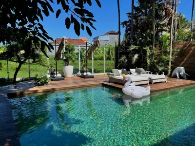 a swimming pool with a couch and chairs in a house at 450 квадратных метров, Вид на Рисовое Поле и Лес in Kerobokan