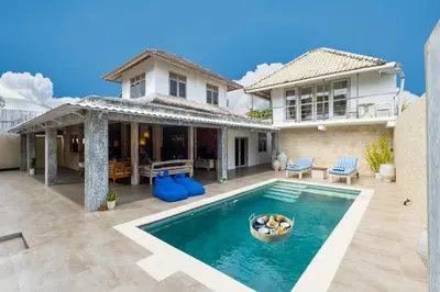 a villa with a swimming pool in front of a house at Villa Bella Vista by Pertama Management in Seminyak
