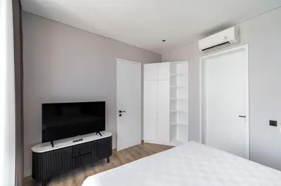 a white bedroom with a bed and a tv at Luxury Haven Stunning 2Br in Umalas Canggu in Kerobokan