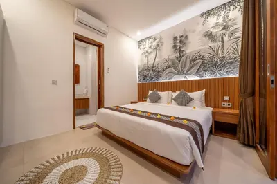 a bedroom with a large bed and a painting on the wall at Umasuka Villa in Denpasar