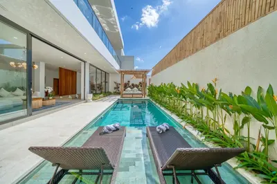 an indoor swimming pool with two chairs and a swimming house at Villa Kangla - 3BR Luxurious Villa Seminyak in Seminyak