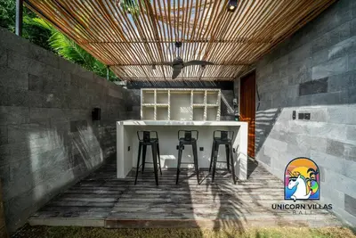 a patio with a bar with stools under a wooden ceiling at SOHO Seminyak 2 - by Unicorn Villas Bali in Seminyak