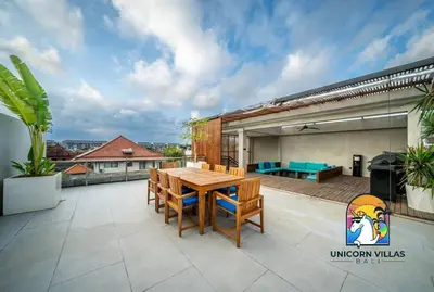 a patio with a wooden table and chairs on a roof at SOHO Seminyak 2 - by Unicorn Villas Bali in Seminyak