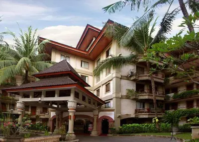 a large building with palm trees in front of it at Jayakarta Bali Apartment 6417 in Seminyak