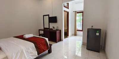 a bedroom with a bed and a dresser and a television at Kusuma Homestay Kerobokan in Kerobokan