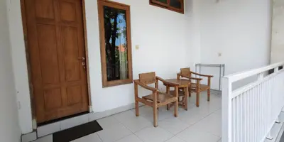 a porch with two chairs and a wooden door at Kusuma Homestay Kerobokan in Kerobokan