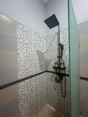 a shower with a glass door in a bathroom at Dara House in Kuta