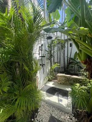 a garden with palm trees and a walkway at The Mia Bali in Kerobokan