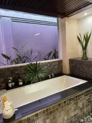 a bath tub in a bathroom with a window at The Mia Bali in Kerobokan