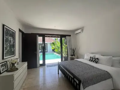 a bedroom with a bed and a sliding glass door at The Mia Bali in Kerobokan