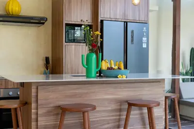 a kitchen with a counter with three stools at Villa Casa Del Sol Umalas in Kerobokan