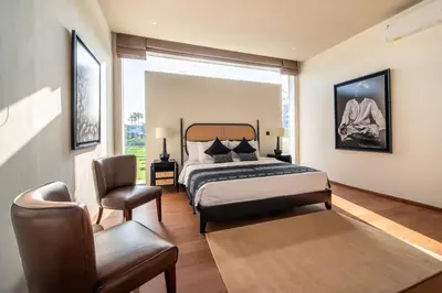 a bedroom with a bed and a chair and a window at Villa Charleston Umalas in Kerobokan