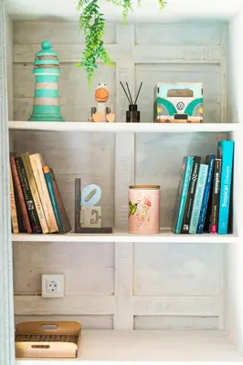 a book shelf with books and other items on it at SooBali Mint Cottage Sanur 1BR in Sanur