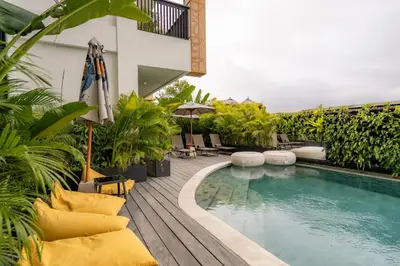 a pool on a patio with chairs and an umbrella at Sunny Nine Villa by Betterplace in Canggu