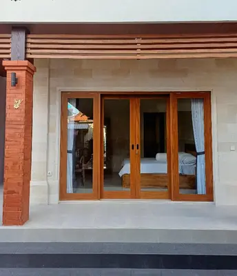 a house with glass doors with a bed in it at Surya Homestay in Seminyak