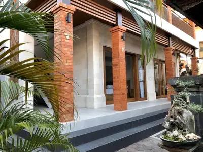 a house with a brick building with a palm tree at Surya Homestay in Seminyak