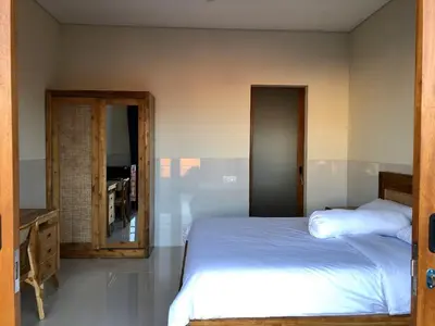 a bedroom with a white bed and a mirror at Surya Homestay in Seminyak