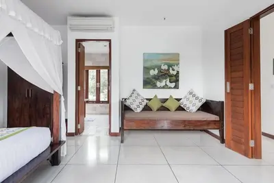 a bedroom with a bench with pillows on it at Villa Annecy in Seminyak