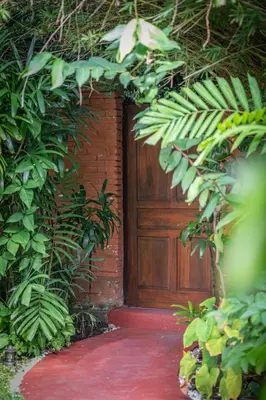 a wooden door in a brick building with plants at Jungle Wave Villa in Central Seminyak in Seminyak