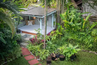 a small bedroom in a garden with plants at Jungle Wave Villa in Central Seminyak in Seminyak