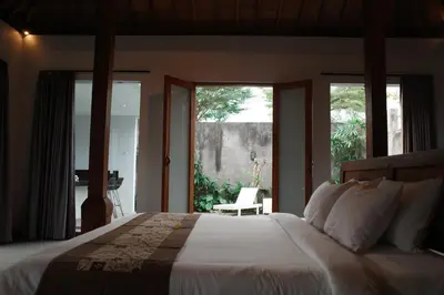 a bedroom with a large bed with a large window at The Riang Villa in Kerobokan